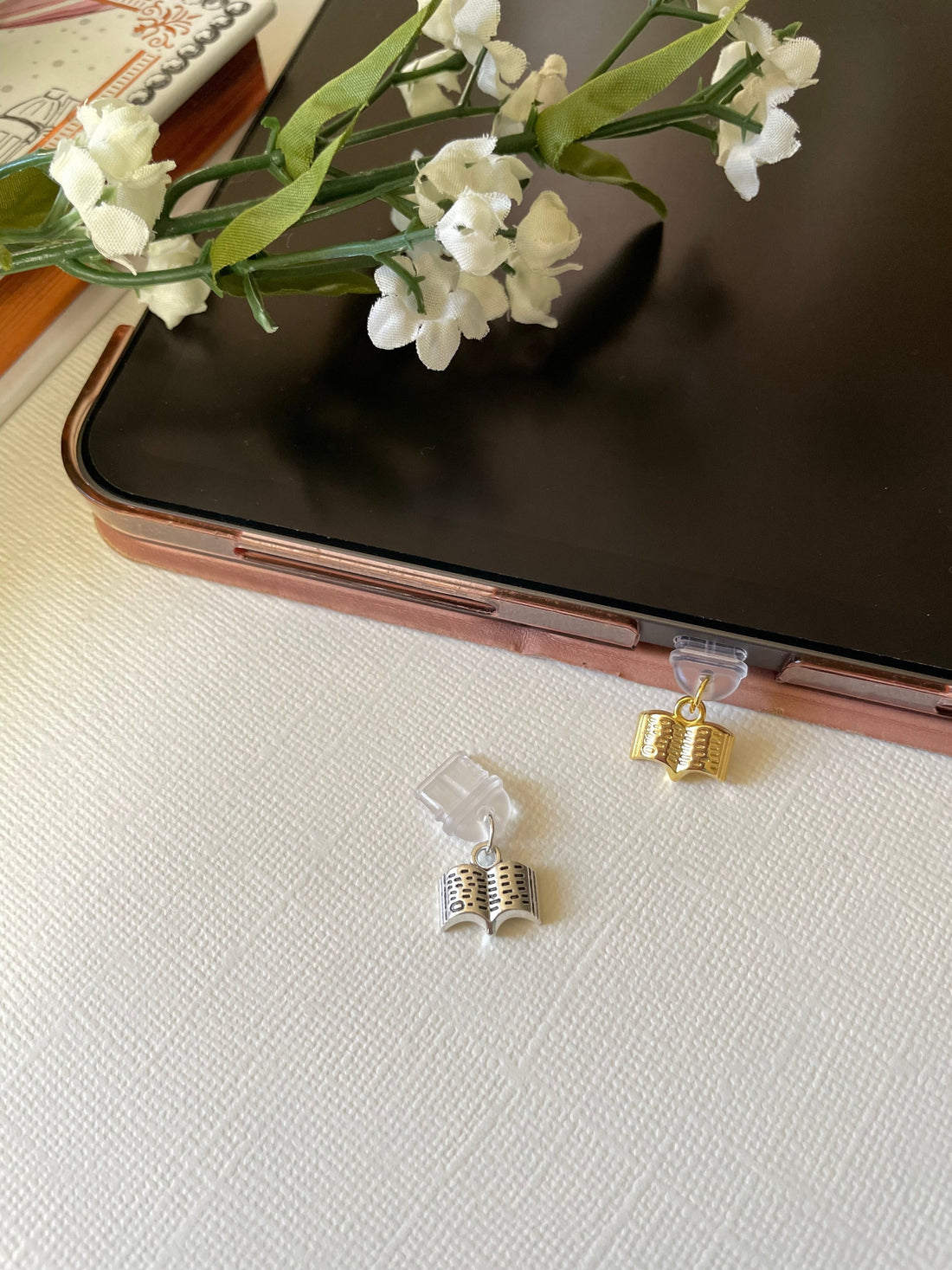 Close-up of a Kindle charm dust plug inserted into a USB-C port, featuring a decorative design for book lovers