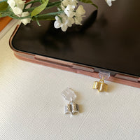 Close-up of a Kindle charm dust plug inserted into a USB-C port, featuring a decorative design for book lovers